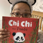 Woman in Panda headband peeking behind a red book with panda on it