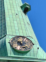 Close up of clock and bell hanging off the side of the spire of St. James's Catholic Cathedral in Riga
