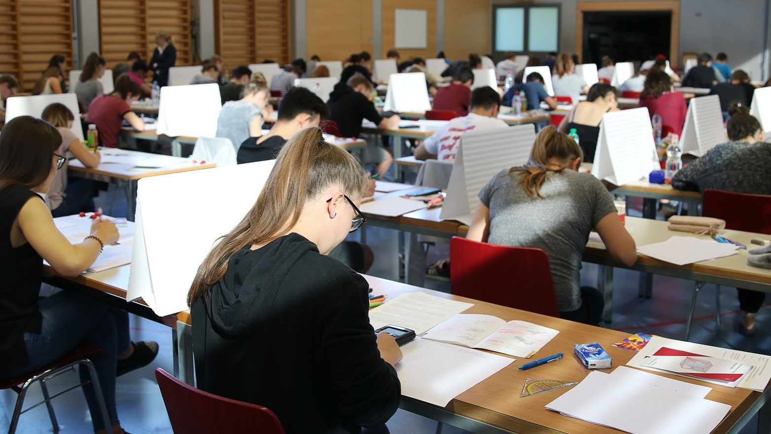 alt="Schülerinnen und Schüler legen in der Turnhalle der Kantonsschule Reussbühl ihre Maturaprüfungen ab." (Bild: Kantonsschule Reussbühl / Regula Schöb)