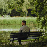 Ein Mann sitzt neben einer Geisterfrau im Park
