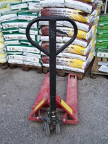 Handhubwagen vor einer Palette Blumenerde