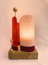 Luminaire avec socles de béton et tissu en rouge et blanc.