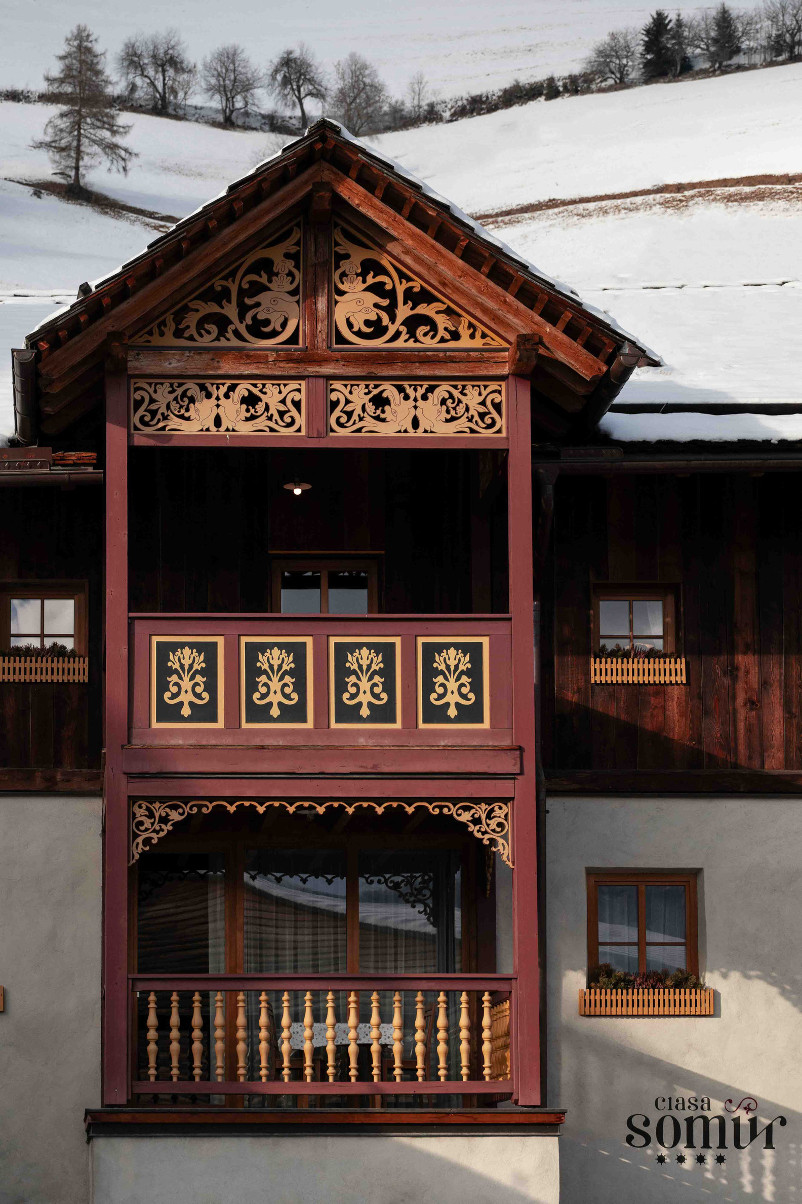 Aussenfassade mit verziertem Holzbalkon und Dachgiebel des ältesten Hauses im Gadertal - Ciasa Somuer • Member of Mountain Hideaways ©Marika Unterladstätter