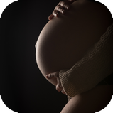 Photo de profil d'un ventre de femme enceinte en clair obscure
