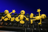 3 kleine gelbe Mänchen arbeiten auf der Tastatur