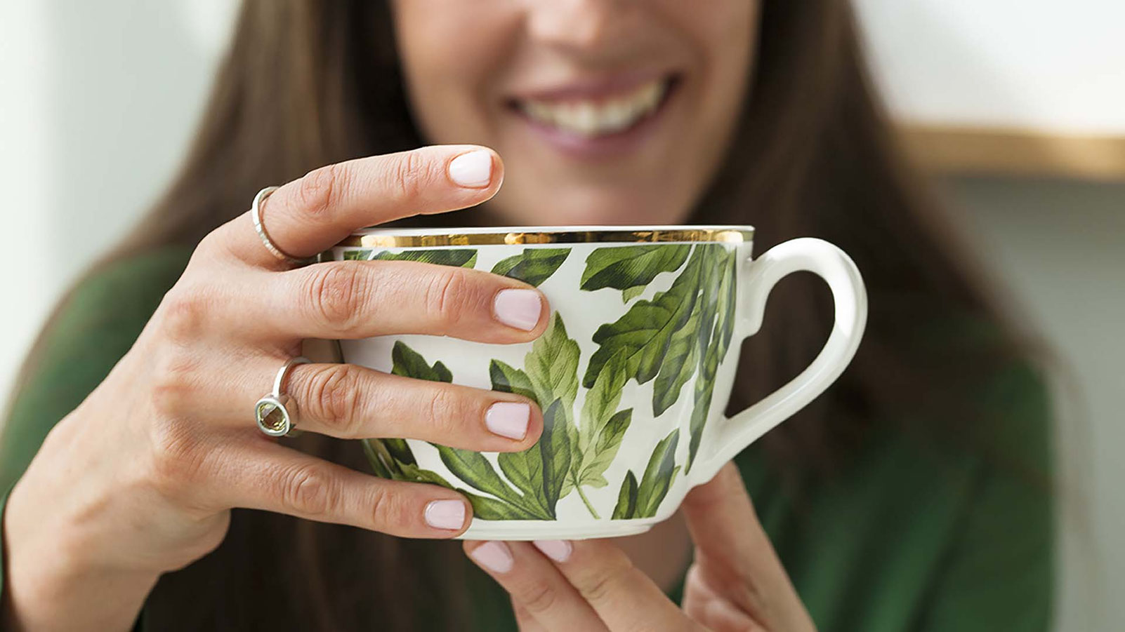 jeune femme souriante portant une bague en argent et citrine qui tient une tasse de thé