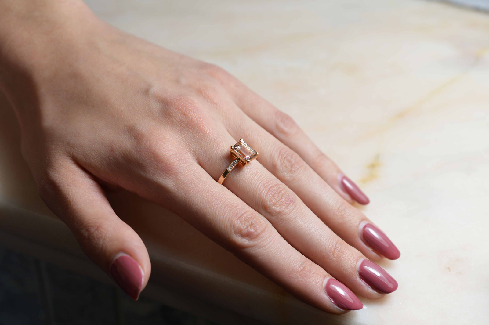 bague en or rose 18 carats sertie d'une pierre morganite et de 6 diamants naturels portée sur main de femme