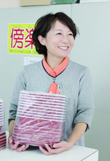 検品した食品容器を店頭に並べる知名恵子さん=まるわ包装