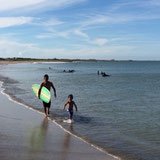 海でサーフボードを持つホスト