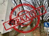 Großes gelbes Haus mit einem weißem Streifen in der Mitte und ein Verkauft Banner quer in rot darüber