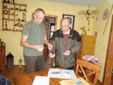 Gebhard Edner (re.) zeigt Rainer Heinrich die NABU-Auszeichnungsmappe "Schwalbenfreundliches Haus" (Foto: Gudrun Edner)