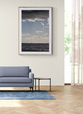 Photo of a living room with a blue sofa and a Delphicaphoto fine art print of the sea with clouds