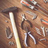 Ansammlung von Werkzeug wie Hammer, Zangen, Schraubenzieher, Messer dekorativ platziert
