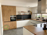 Grifflose U-Form Küche in weiß und Holzelementen mit matt, schwarzer Glasnischenplatte von Schreinerei Holzdesign Ralf Rapp in Geisingen