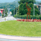 Public iron sculpture by Paolo Grassi installed in the Losone roundabout near Locarno, composed of rising numbered elements.