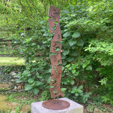 Corten steel sculpture by Paolo Grassi with vertical numeric sequence rising into the air.