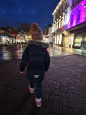 Kind in weihnachtlich beleuchteter Straße