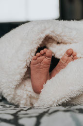 deux petits pieds de bebe qui sortent de la couverture