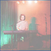 Frau auf der Bühne am Klavier singt