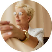 Porträt einer reifen, stilvollen Frau mit Kurzhaarschnitt und Brille in heller Businesskleidung – Blick in die Ferne.