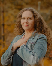 Susanne Kruse mit ruhigem, offenen Blick und Hand auf dem Herzen – Symbol für Bewusstsein, Weiblichkeit und authentische Führung in ihren Retreats in Mecklenburg-Vorpommern.