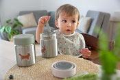 Kind mit Thermobehälter, Lätzchen und Kindergeschirr