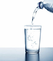 Wasser wird aus einer Flasche in ein Glas geschüttet