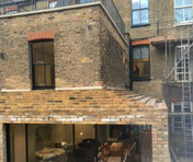 Stepped buff brick slip feature panels installed on roof at rear of property.