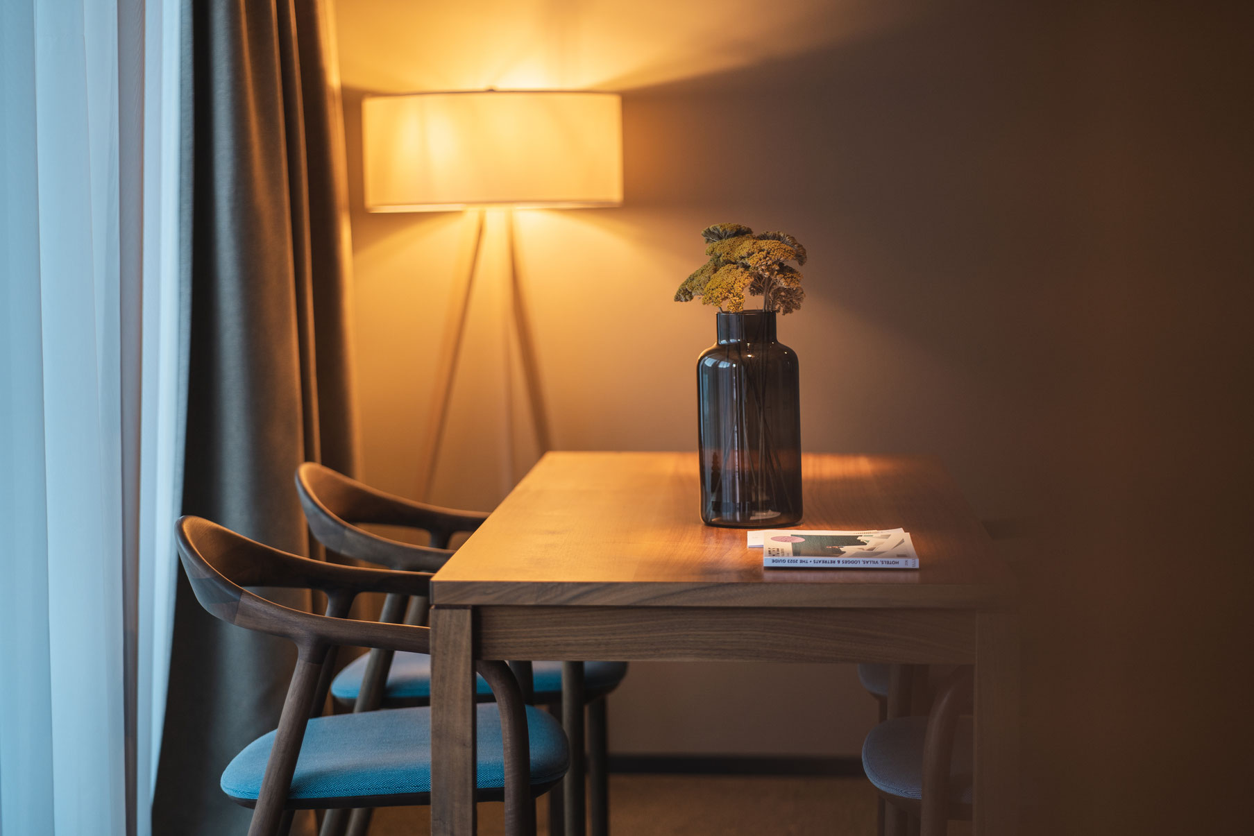 A cosy seating area at the Garberhof with a wooden table, stylish chairs and warm lighting.