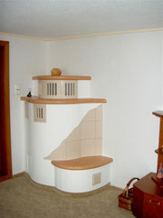 platzsparender Kachelofen mit Feuerungstür vom Nachbarraum