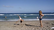 Deux enfants s'amusant sur une plage de sable de la Côte d'Opale, l'un faisant une roue, illustrant un séjour familial réussi au Gîte Saint Lambert.