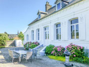 Grande terrasse aménagée avec barbecue et table de jardin devant la façade fleurie du Gîte Saint Lambert sur la Côte d'Opale.