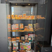 Das Bild zu Männerquatsch Podcast Folge 196 zeigt die Männerquatsch Podcast Spiel des Lebens / Game of Life / Jinsei Game Vitrinenausstellung in der Retro Area auf der Gamescom 2025.