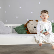 Kind imSchlafsack to go von Träumeland sitzend auf Kinderbett