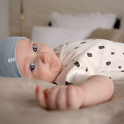 Baby mit Body & Beanie von LÄSSIG auf Wickelunterlage