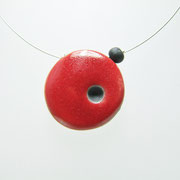 collier rond et plat avec un petit point noir sur fond rouge