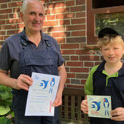 Heinrich Evers und Enkelsohn Henry präsentieren stolz Plakette und Urkunde