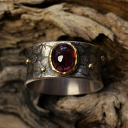 Silberring, geschwärzt, mit Blumenmotiv. Rhodolith in 750er Gelbgoldfassung.