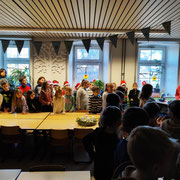 Eine Lehrerin liest ein Gedicht vor. Alle Kinder hören zu. 