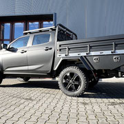 Pickup-Ladeflächenumbau mit klappbaren Bordwänden, hohem Frontbügel, seitlichen Toolboxen und praktischem Dachträger