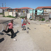 Jungs spielen Fussball mit einem aus Tueten zusammengekneulten Ball im Township Khayelitsha bei Kapstadt