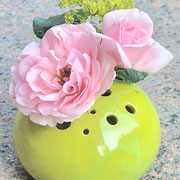 kugelige Vase mit kleinen Löchern in denen Rosenblüten stecken