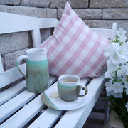 Tasse, Teller, Krug auf Gartenbank arrangiert