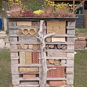 Bienenhotel gestaltet mit Lehm, Bambus und Schilfröhrchen und Pflanzendach