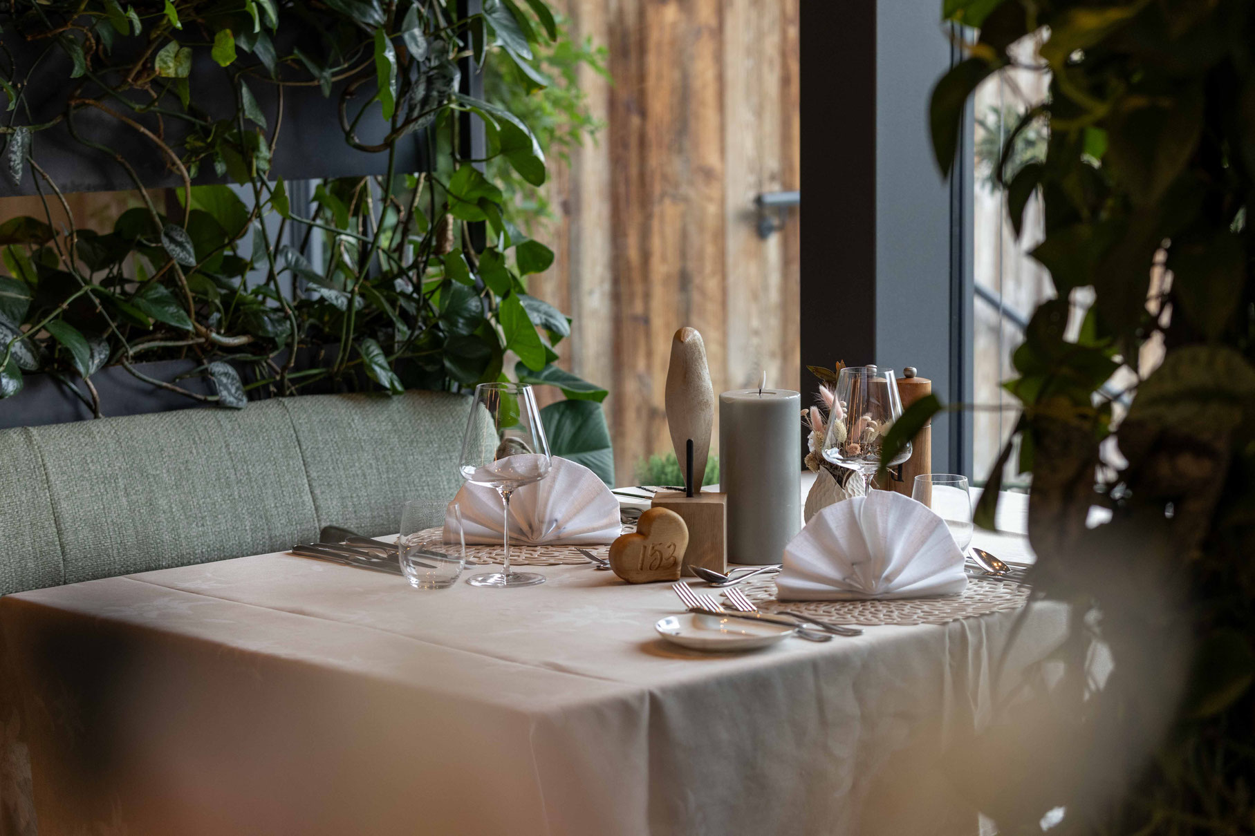 Liebevoll gedeckter Tisch im Restaurant des DER ENGEL im Tannheimertal. Elegante Tischdekoration, hochwertige Gläser, natürliche Materialien und üppiges Pflanzengrün schaffen ein stilvolles Ambiente für genussvolle Stunden in entspannter Wohlfühlatmosphär