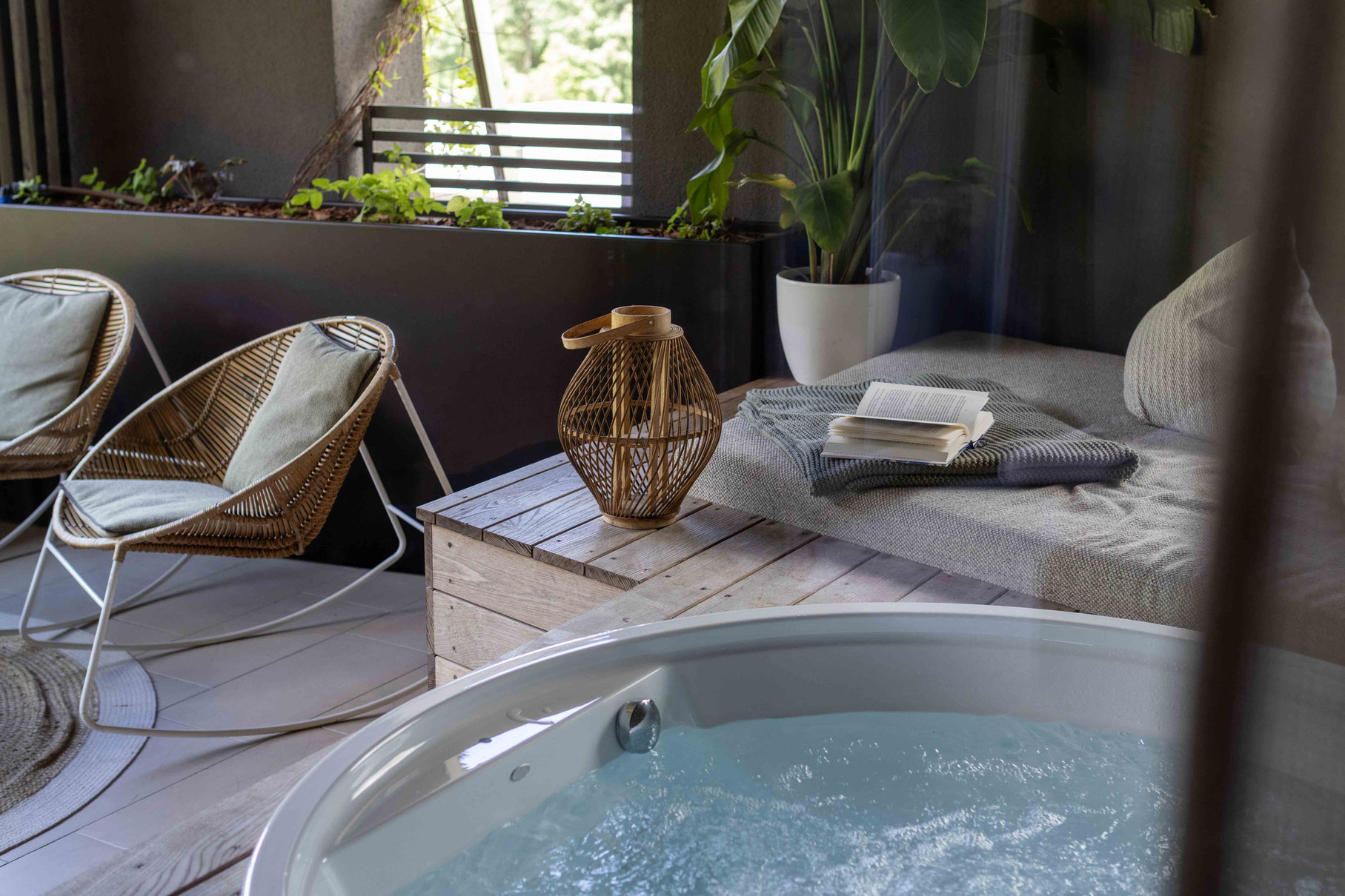 A whirlpool, a cosy lounger with a book, and stylish lounge chairs in the wellness area of the PETRUS boutique hotel in Reischach-Bruneck • South Tyrol, which invites you to enjoy peace and relaxation in a laid-back atmosphere.