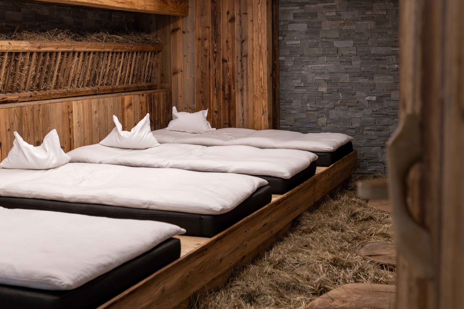 A relaxation room with comfortable loungers, natural wooden features and hay in the wellness area of the Boutique Hotel PETRUS in Reischach-Bruneck • South Tyrol, designed for rest and relaxation.