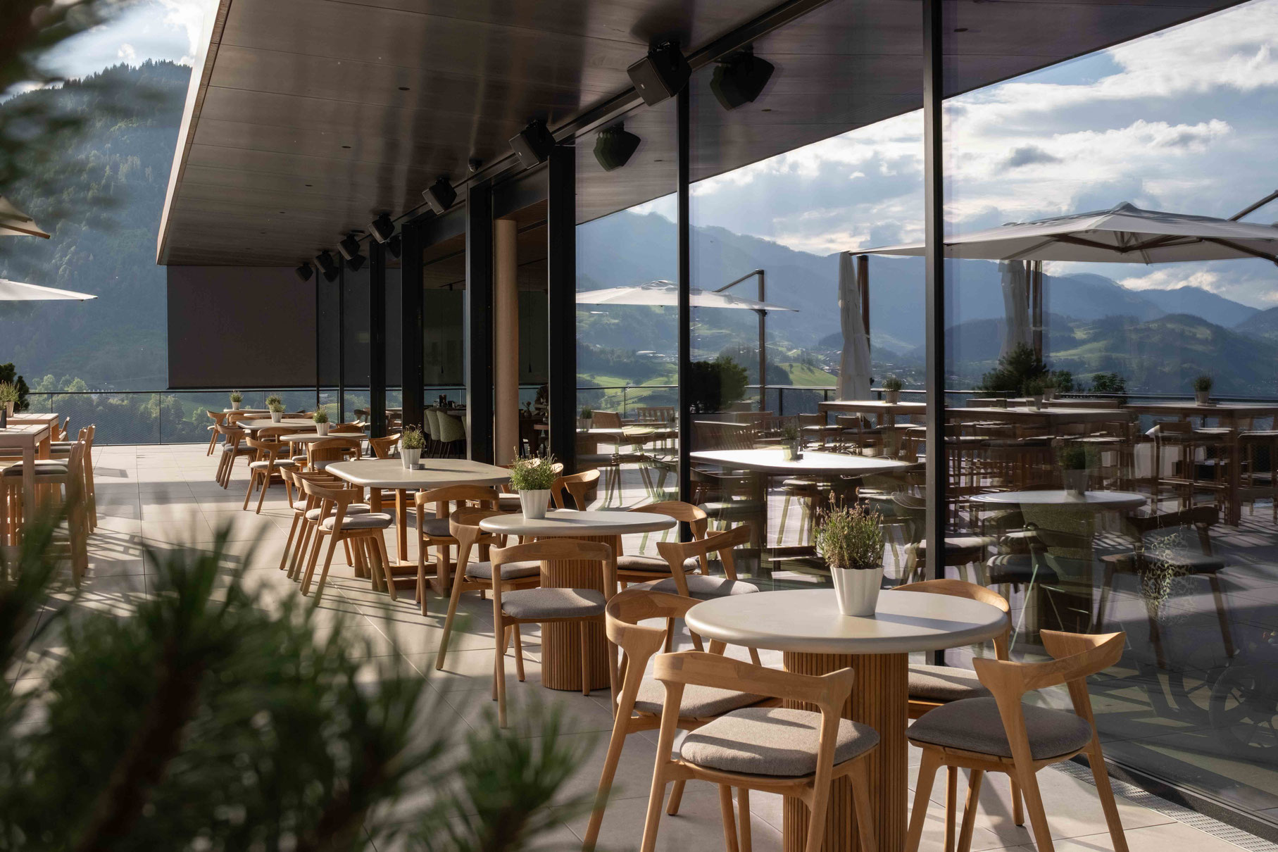 Sonnenterrasse des OBERFORSTHOF – Familien- und Wellnesshotels in St. Johann im Pongau, Salzburg, mit Sitzplätzen und Blick auf die umliegende Berglandschaft.