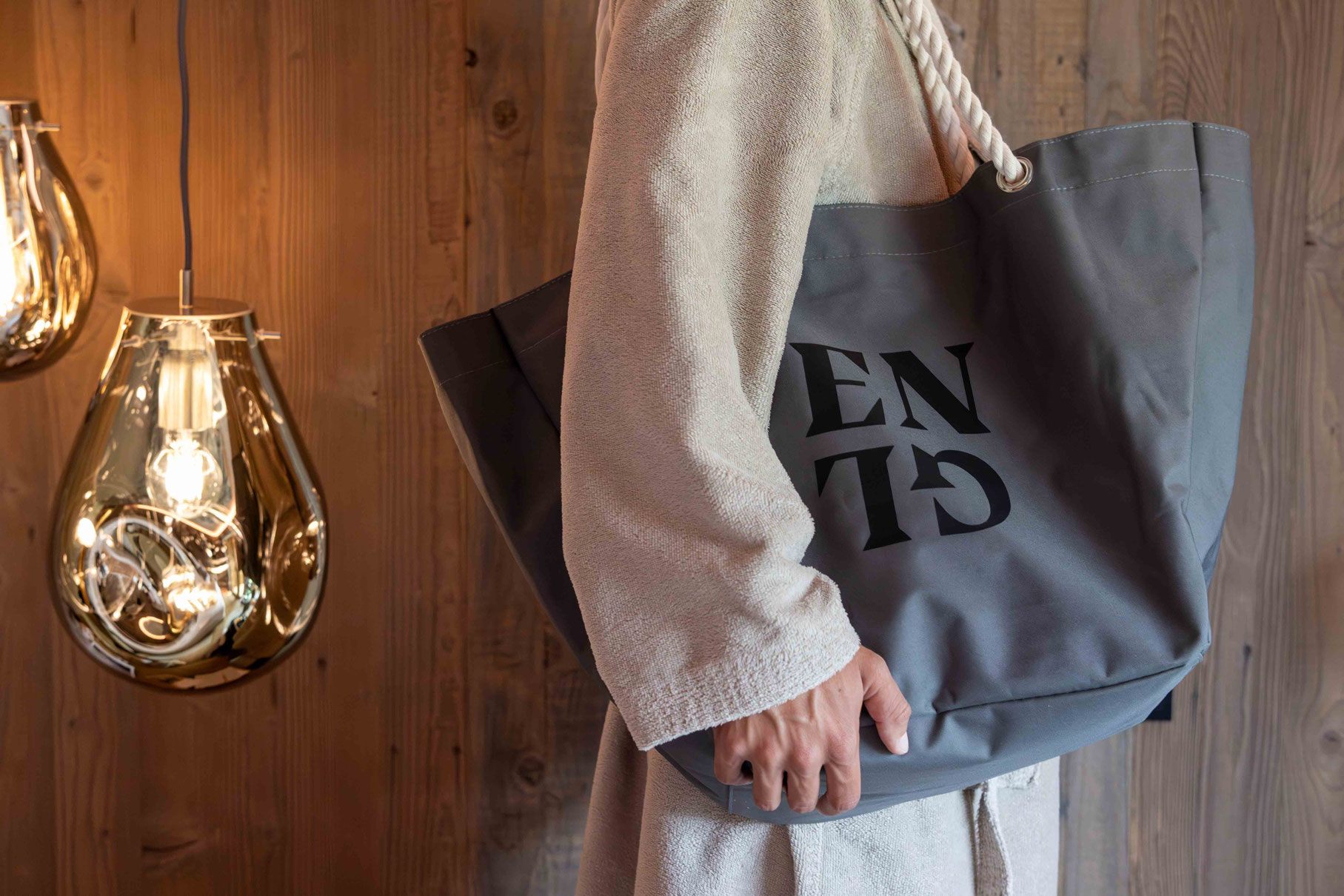 Gast im Bademantel mit Wellnesstasche im DER ENGEL im Tannheimertal. Hochwertige Ausstattung, natürliche Materialien und stilvolle Details unterstreichen das entspannte Wellnesserlebnis im Hotel.