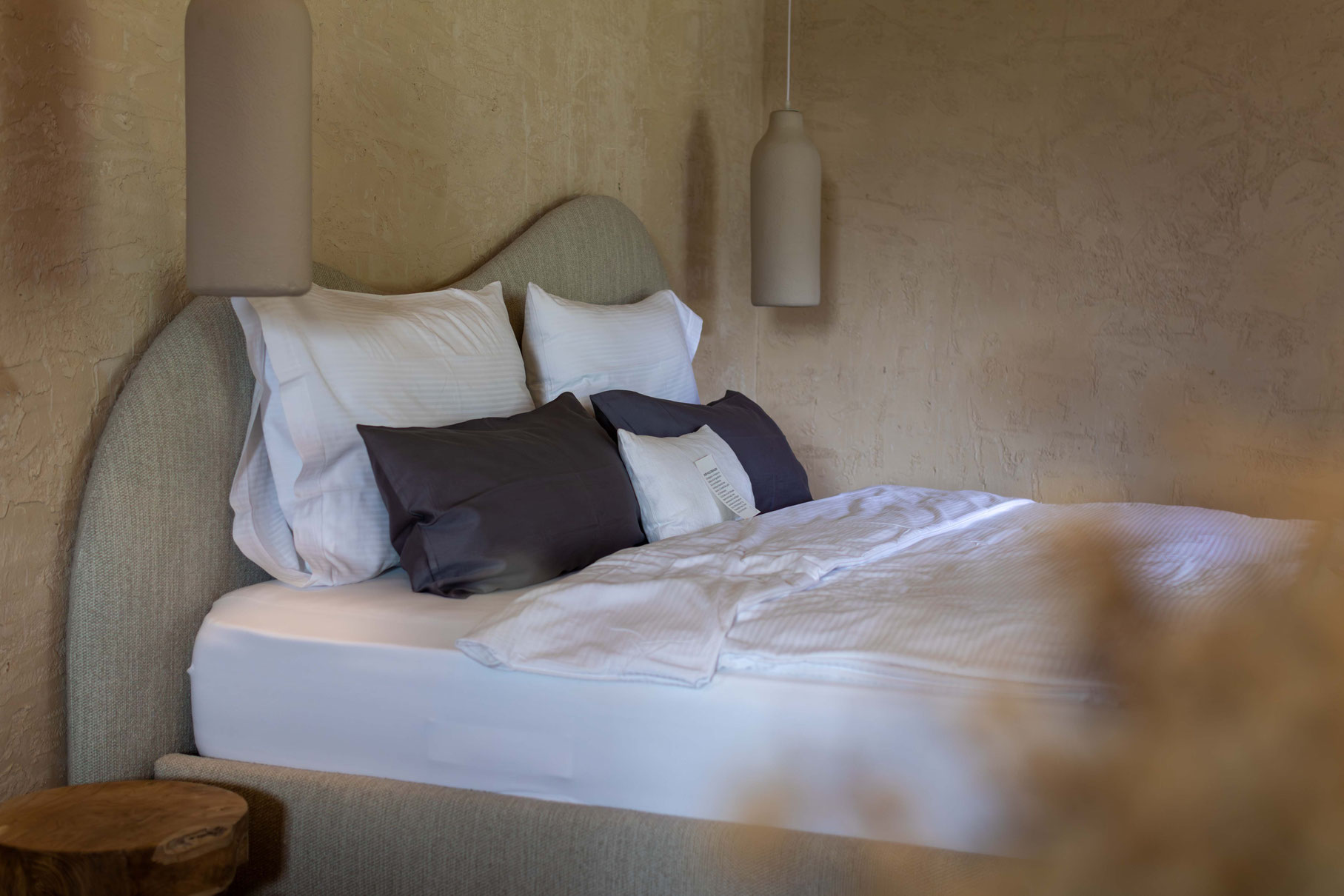A stylishly furnished double room with a comfortable bed, natural materials and soft lighting at the PETRUS boutique hotel in Reischach-Bruneck • South Tyrol, designed for restful nights and relaxing breaks.